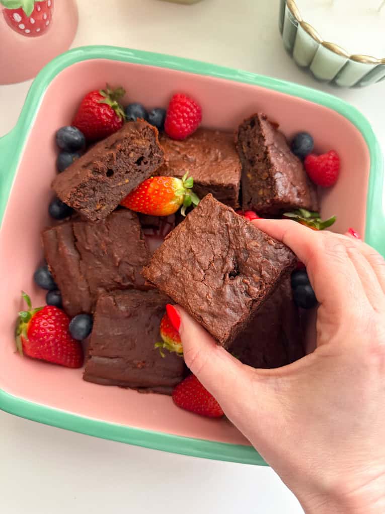 Brownies di patate dolci tagliati a quadrotti, serviti in una pirofila e guarniti con fragole intere e lamponi.