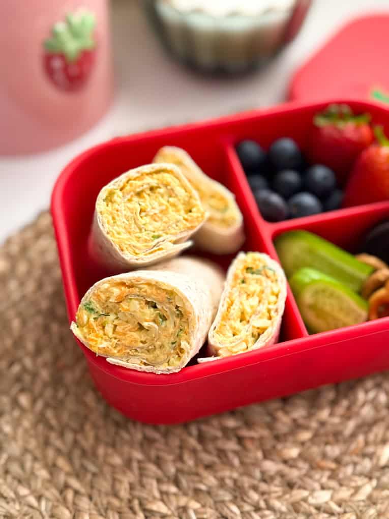 Veggie Cheese wraps served in a bright red child's lunchbox along with other lunchtime treats.
