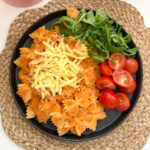 Butterbean sauce mixed into bow shaped pasta and served with chopped cherry tomato's and salad leaves, garnished with grated cheese.