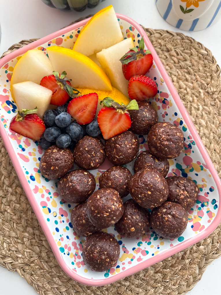 No Bake Chocolate Weetabix Bites presented in a rectangle bright coloured dish with chopped,fresh fruit.