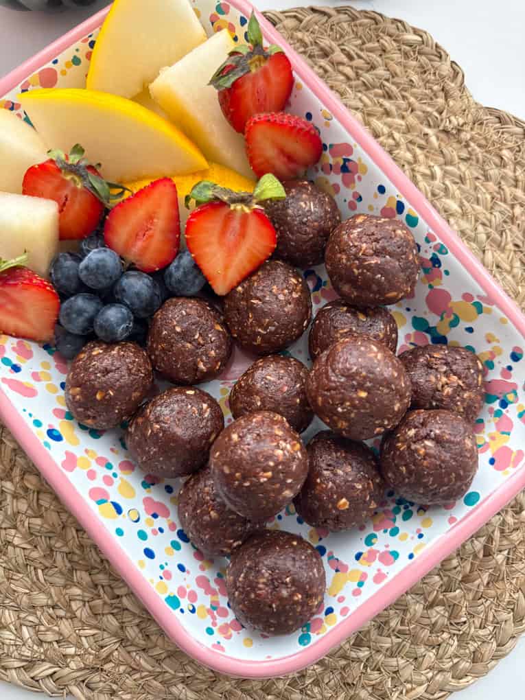 No Bake Chocolate Weetabix Bites presented in a rectangle bright coloured dish with chopped,fresh fruit.