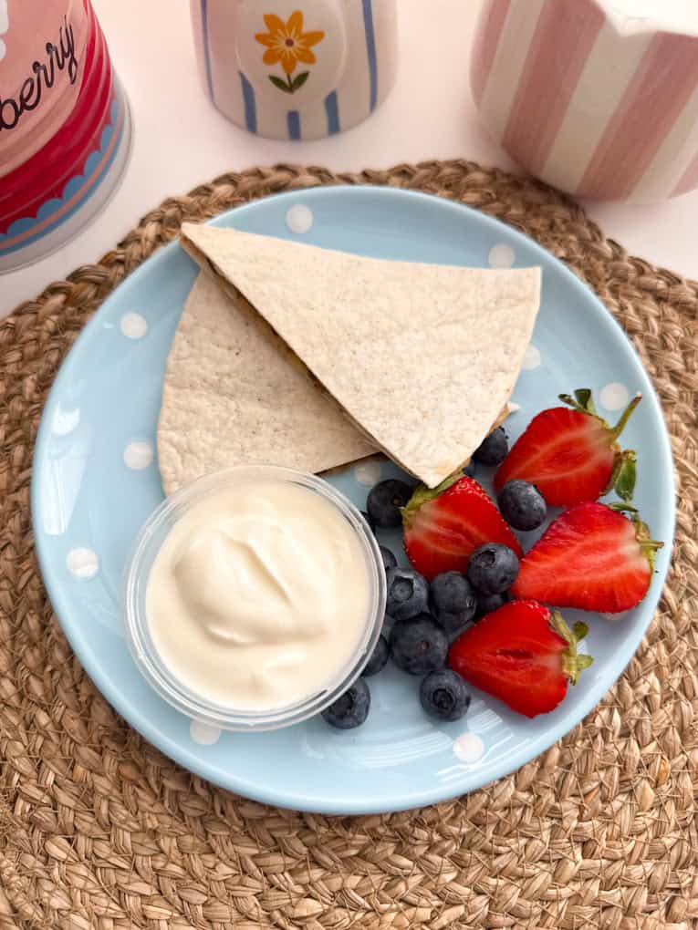 Chocolate banana wraps arranged on a baby blue coloured round plate with white polka dots and served with fresh berries and yogurt.